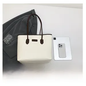 Detail view of large capacity cream tote bag with brown handles and office accessories