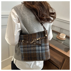 Détail du sac seau vintage en laine à carreaux bleus et marrons avec lanières en cuir