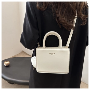 Detailed view of white faux leather crossbody bag with a round mini pouch charm accessory