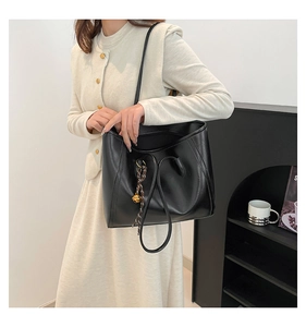 Close-up of the black faux leather tote bag with elegant drawstring and metal charm detail