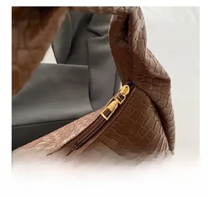 Detailed close-up of the smooth gold-tone metal zipper on a brown textured leather tote bag