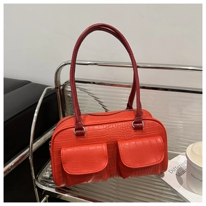 Detail of orange faux crocodile skin texture and dual front pockets on stylish tote bag
