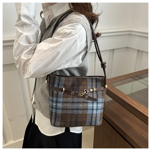Vue latérale d'un sac seau vintage en tweed avec bandoulière en cuir brun et boucle
