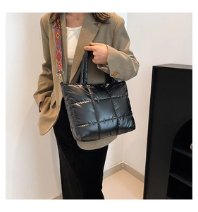 Détail du sac cabas matelassé noir avec une bandoulière géométrique colorée sur l'épaule