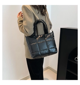 Sac fourre-tout noir matelassé brillant porté par un mannequin dans un cadre minimaliste chic