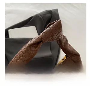 Detail of dark brown leather tote featuring a unique knotted handle and woven texture