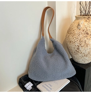 Detail of light blue faux fur tote bag with brown leather strap in a minimalist setting