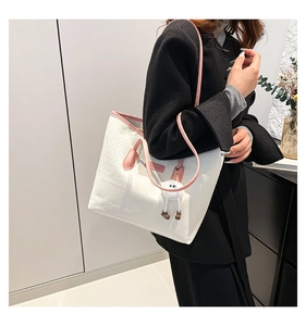White embossed tote bag featuring pink handles and a cute plush doll charm accessory
