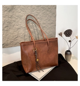Detailed macro view of vintage brown tote bag texture with decorative bell and woven cord