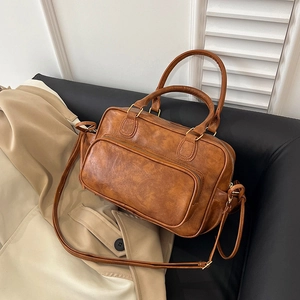 Vintage brown Boston handbag with top handles and adjustable strap on beige coat