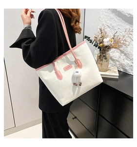 Detail of white large tote bag with pink straps, square texture, and plush toy charm