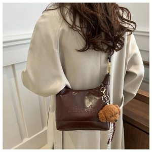Detail of dark brown leather shoulder bag with mioashe embossing and teddy bear charm