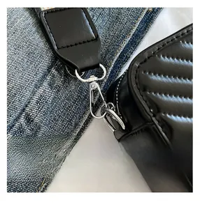 Détail du fermoir métallique argenté sur sac matelassé noir avec bandoulière tissée colorée