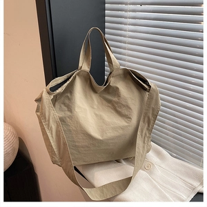 Dettaglio della borsa tote in tela kaki con zip nera su uno sfondo in maglia bianca