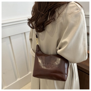 Detail of dark brown leather shoulder bag with embossed texture and metal chain strap