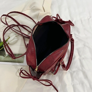 Retro wine red synthetic leather backpack with golden accents and ribbon detailing