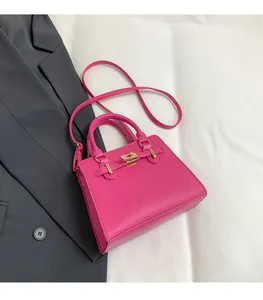 Detailed top view of a hot pink trapezoid handbag with gold hardware on white bedding