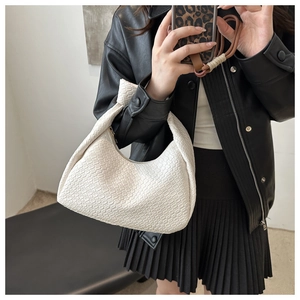 Detailed view of white woven hobo bag showing intricate faux leather texture and minimalist handle