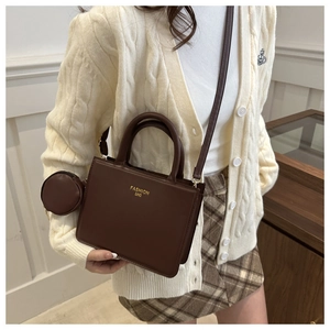 Detail of dark brown leather crossbody bag with small round coin purse and adjustable strap