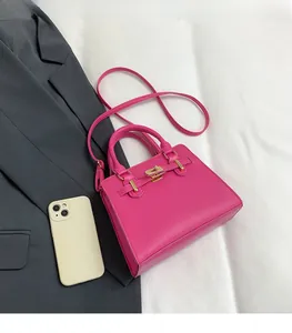 Pink top-handle handbag size comparison with a smartphone on white fabric background