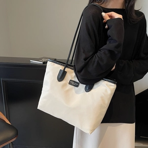 Minimalist beige tote bag with black handles shown by model for casual daily commuting
