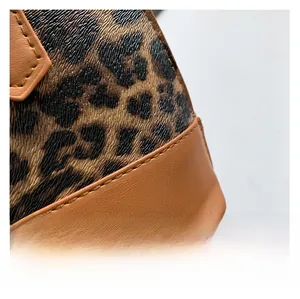 Close-up detail of leopard print fabric and premium brown leather stitching on handbag