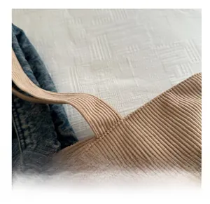 Detailansicht des Cord-Schultergurts mit blauen Denim-Nähten an der Tragetasche
