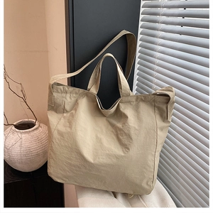 Borsa tote in tela beige minimalista con tracolla mostrata in un ambiente moderno