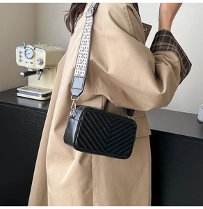 Détail du sac caméra noir à surpiqûres en V avec bandoulière large et finitions argent