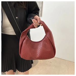 Detailed close-up of brick red woven PU leather hobo bag with knotted handle detail