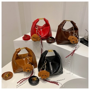 Detail view of stylish Hobo bags in four colors with plush dog charms and gold hardware