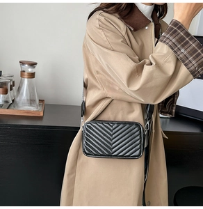 Détail d'un sac bandoulière noir matelassé chevrons porté avec un trench-coat kaki