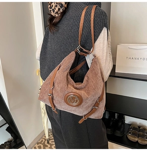 Détail du sac cabas en daim avec logo M métallique et bandoulière sur mannequin