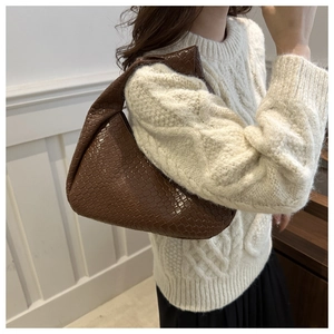 Brown faux crocodile embossed half-moon shoulder bag styled with a white cable knit sweater