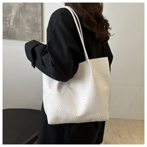 Detail of white woven texture tote bag featuring minimalist rectangular structure and shoulder strap