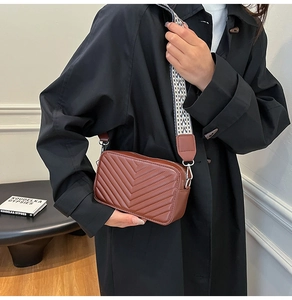 Détail d'un sac bandoulière matelassé marron avec une large sangle tissée géométrique