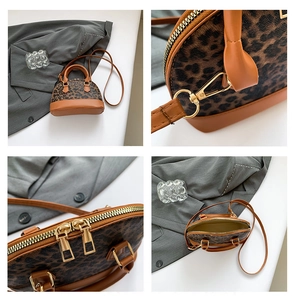 Detail view of leopard print shell bag featuring golden zippers and adjustable leather strap