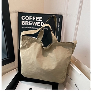 Dettaglio della borsa tote in nylon kaki con manici resistenti e texture minimalista