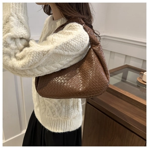 Detailed view of dark brown woven crescent bag with decorative knotted shoulder strap