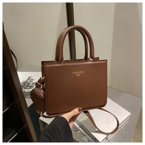 Close-up of brown faux leather handbag with detachable mini pouch and gold fashion text