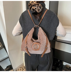Détail d'un sac à dos en velours côtelé marron avec logo M et bretelles en cuir
