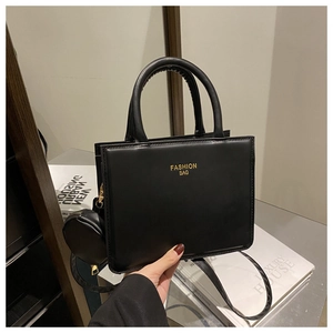 Close-up of black leather tote bag featuring gold lettering and small coin purse