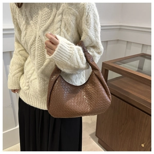 Detailed view of brown woven leather crescent shoulder bag with intricate cross-weave texture