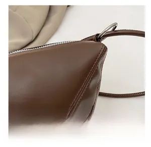 Detail showing high-quality stitching and silver zipper on dark brown dumpling bag