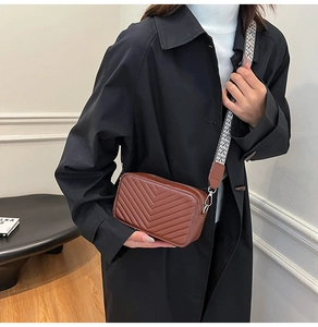 Détail du sac bandoulière marron avec surpiqûres en V et large bandoulière géométrique