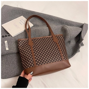 Detailed view of vintage pattern tote bag with leather straps on a grey wool coat