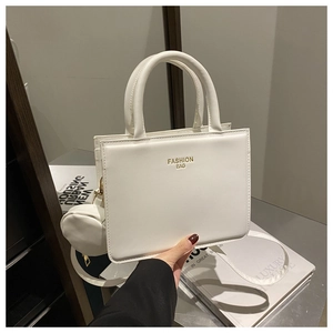 Detailed view of a white minimalist handbag on books with a mini round charm