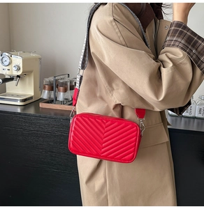 Détail du sac bandoulière matelassé rouge avec sangle tissée large et finitions argent