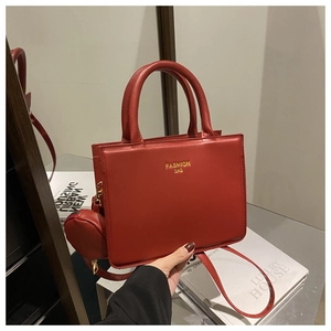 Detail of red leather tote bag with gold lettering and round coin purse attachment