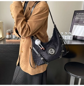 Détail du sac croissant en velours noir avec logo M et charme de monstre en peluche